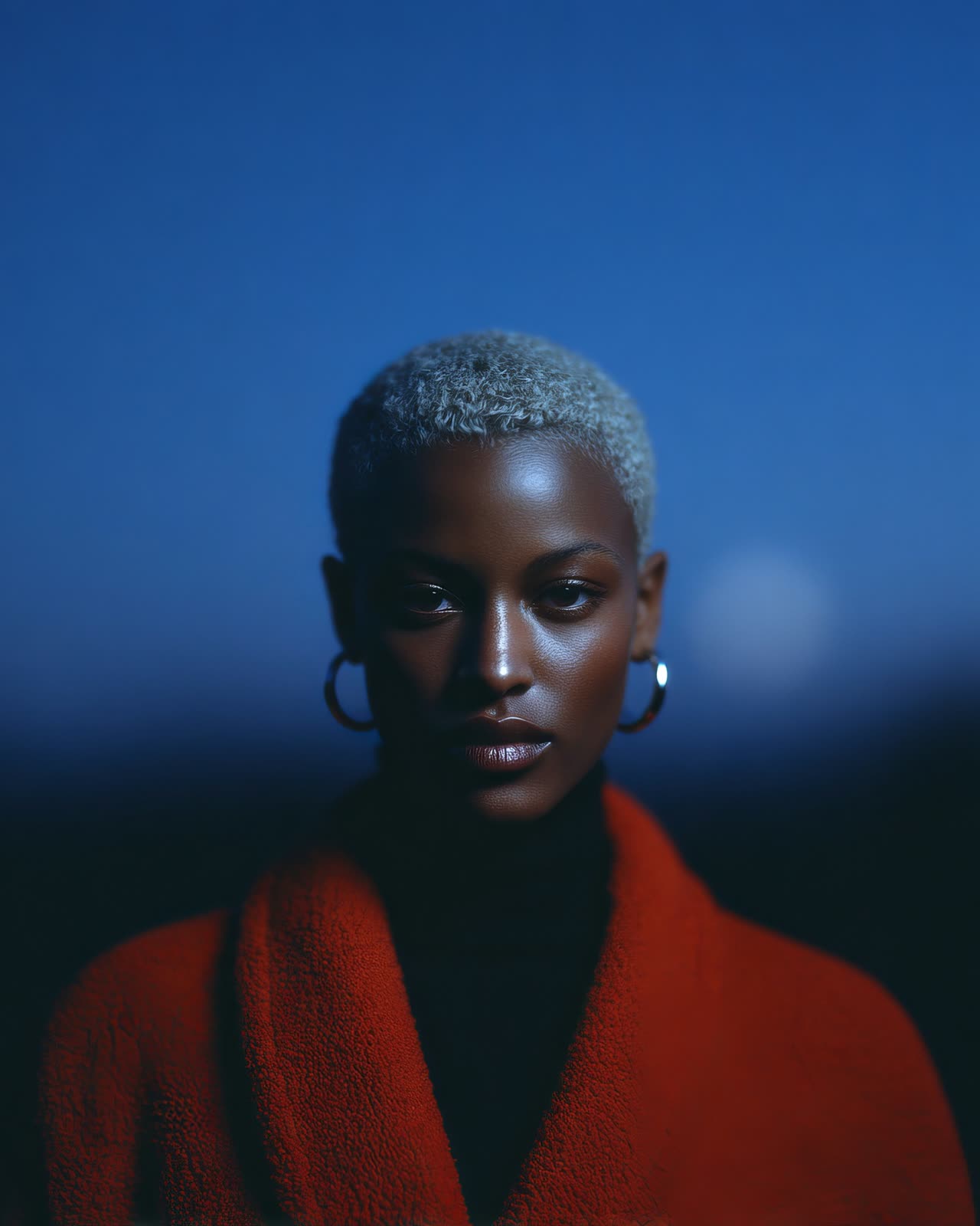 A person in a red coat against a deep blue background